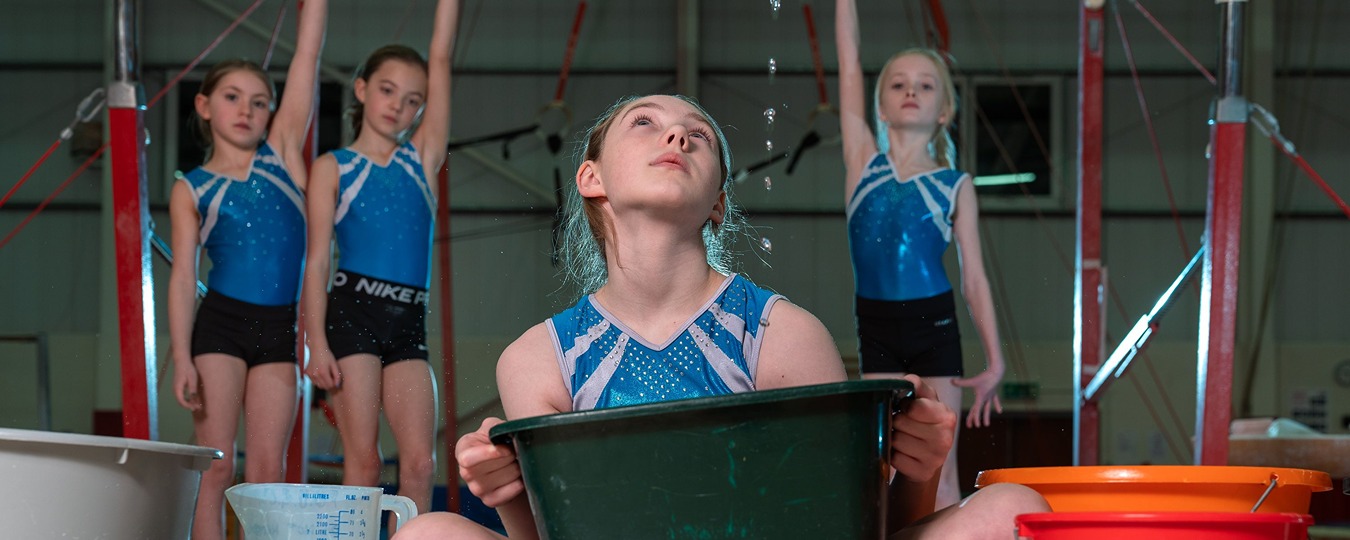 Young gymnast holding bucket catching roof leak