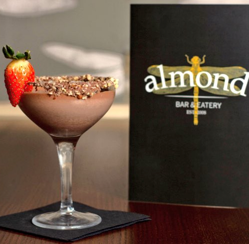Image of delicious looking cocktail from Almond Bar on table with menu next to it and napkin below it. 
