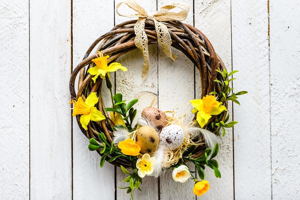 Easter wreath hung on front door and filled with eggs and daffodils