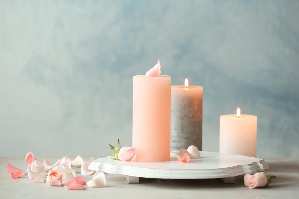 Picture of three pink candles on tray with flower petals