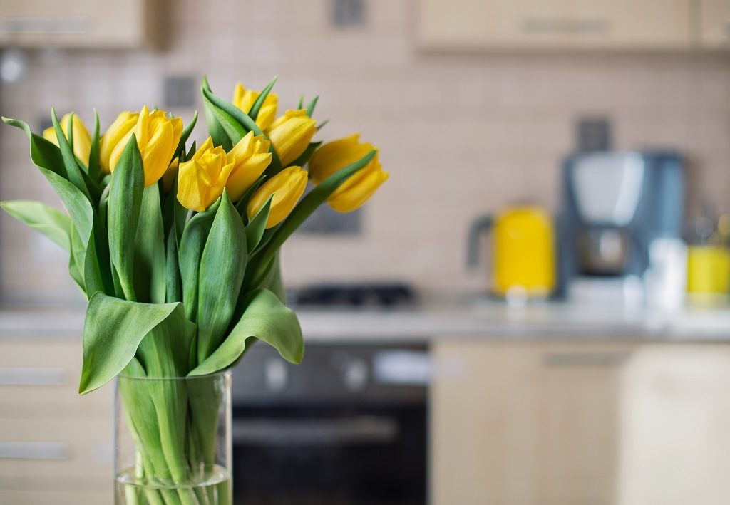 Picture of yellow flowers in the foreground and kitchen in the background