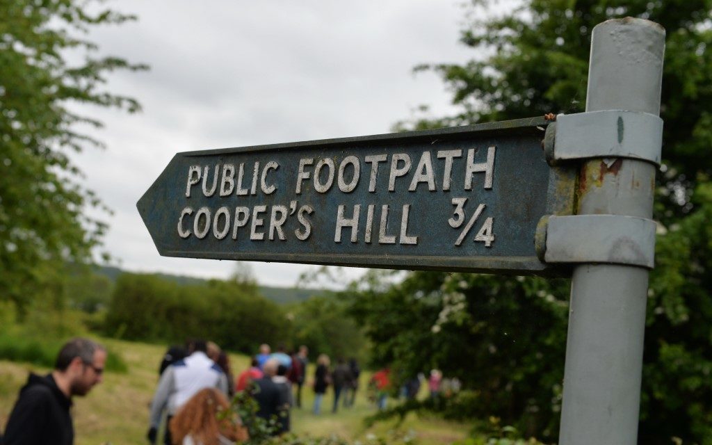 sign pointing to Cooper’s Hill with people attending cheese rolling event