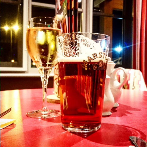 Image taken inside Liverpool pub the Vikings Landing of brightly lit table with half drunk pint and a glass of white wine on table