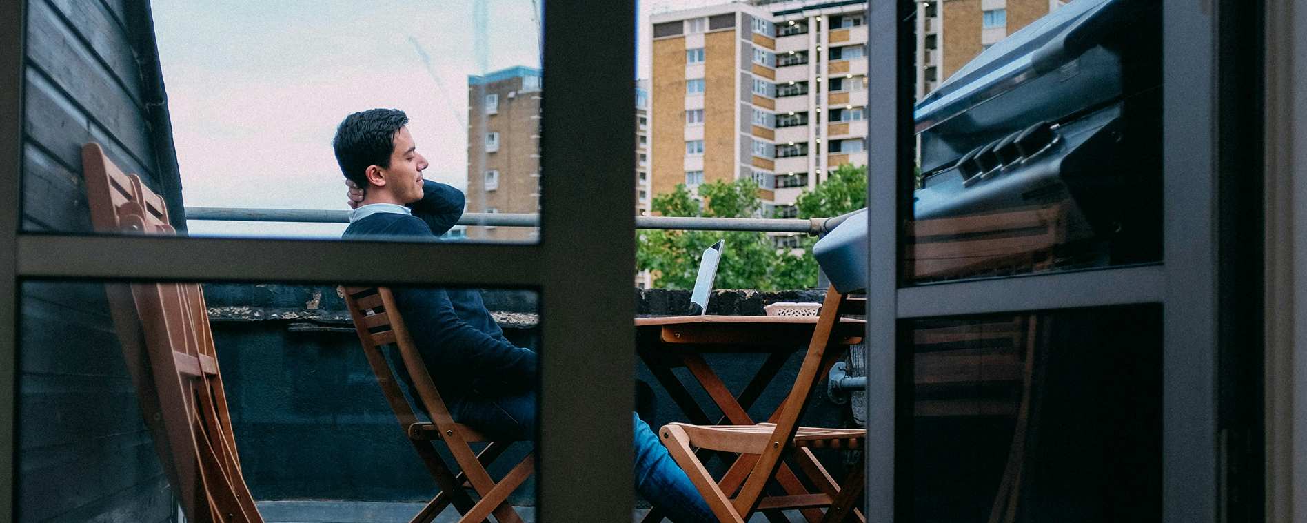 man sat on laptop on balcony