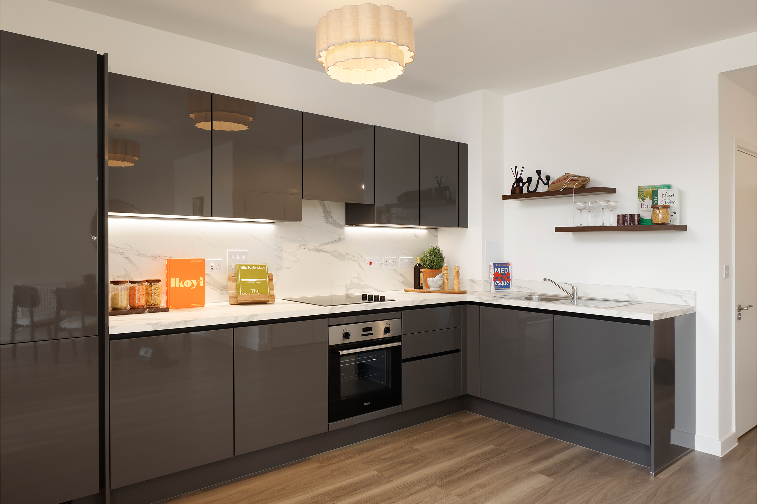 Angled photograph towards grey kitchen with dark wood flooring