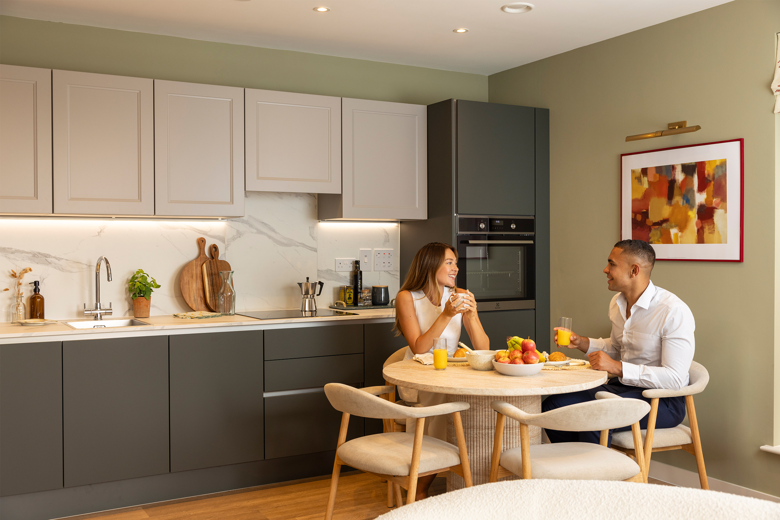 couple sat at the dining table next to the kitchen having breakfast together
